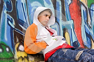 Teenager sitting near a graffiti wall