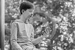 Teenager sitting outdoors with smartphone