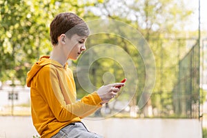 Teenager sitting outdoors with smartphone