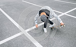 Teenager skateboarder boy with a skateboard on asphalt playground doing tricks. Youth generation Freetime spending concept image