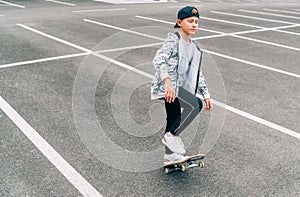 Teenager skateboarder boy with a skateboard on asphalt playground doing tricks. Youth generation outdoor Freetime spending concept