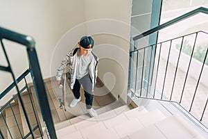 Teenager skateboarder boy with a skateboard going up by staircase home. Youth generation Freetime spending concept image
