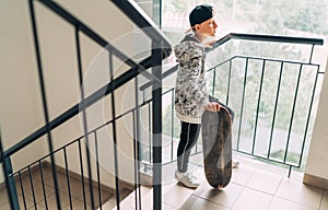 Teenager skateboarder boy with a skateboard going up by staircase home. Youth generation Freetime spending concept image