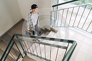 Teenager skateboarder boy with a skateboard going up by staircase home. Youth generation Freetime spending concept image