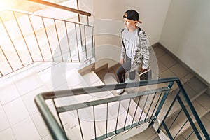 Teenager skateboarder boy with a skateboard going up by staircase home. Youth generation Freetime spending concept image