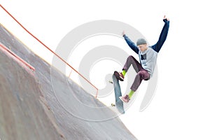 The teenager skateboarder in the cap does a trick with a jump on the ramp in the skatepark. Isolated skater and ramp on
