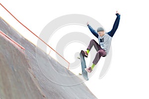 The teenager skateboarder in the cap does a trick with a jump on the ramp in the skatepark. Isolated skater and ramp on photo