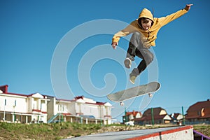 A teenager skateboarder does an flip trick in a skatepark on the outskirts of the city