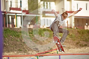 A teenager skateboarder does an ollie trick in a skatepark on the outskirts of the city