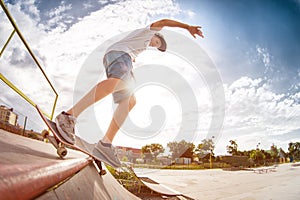 Teenager skater in a cap and shorts on rails on a skateboard in a skate park