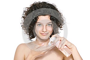 Teenager skincare. Beautiful teenage girl with gorgeous curly hair and green eyes using foaming cleanser. Face washing concept. photo