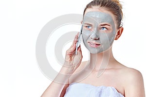 Teenager skincare concept. Young teen girl with dried clay facial mask making phone call