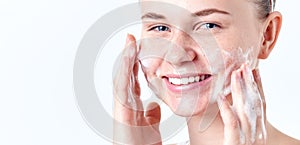 Teenager skincare. Smiling beautiful teen girl with freckles and blue eyes using foaming cleanser. Face washing concept photo