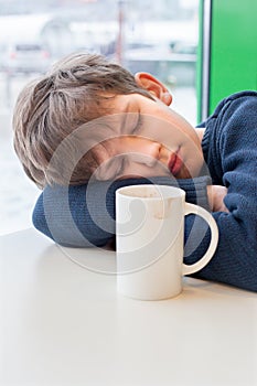 A teenager is sleeping in cafe