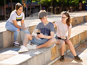 Teenager with smartphone not paying attention to girlfriends outdoor