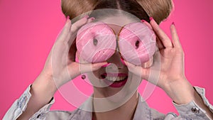 Teenager sniffs the cake and smile. Pink background. Close up. Slow motion