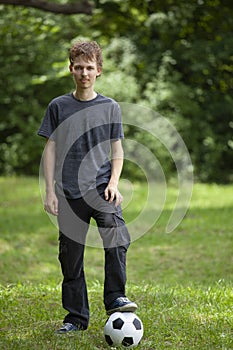 Teenager with soccer football ball on green grass