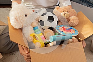 Teenager sorting and collect kid toys, clothes into boxes at home. Donations for charity, help low income families