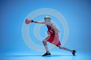 Teenager in sportswear boxing isolated on blue studio background in neon light