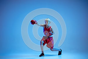 Teenager in sportswear boxing isolated on blue studio background in neon light