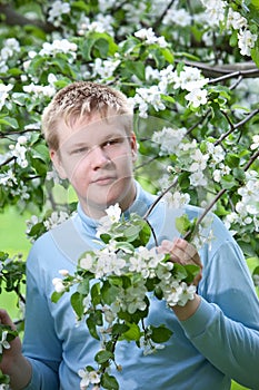 Teenager standing near blossoming apple tree.