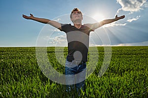 Teenager standing in a wheat field at sunset