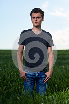 Teenager standing in a wheat field at sunset