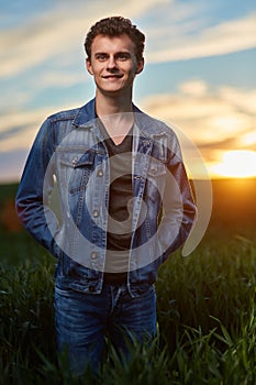 Teenager standing in a wheat field at sunset