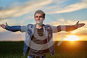 Teenager standing in a wheat field at sunset