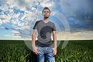 Teenager standing in a wheat field at sunset