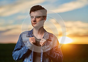Teenager standing in a wheat field at sunset