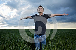 Teenager standing in a wheat field at sunset