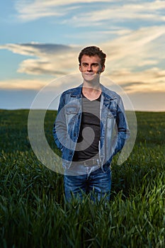 Teenager standing in a wheat field at sunset
