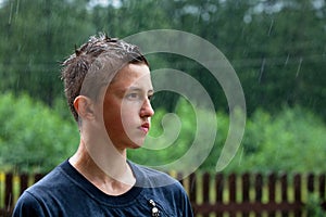 A teenager stands in the rain