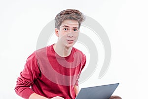 Teenager student with funny face working at laptop on white background