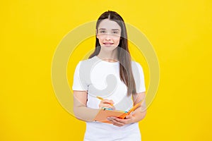 Teenager student girl isolated on yellow background. Cheerful young woman student in shirt hold notebooks showing. High