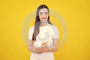 Teenager student girl  on yellow background. Cheerful young woman student in shirt hold notebooks showing. High