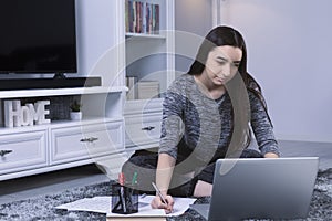 Teenager student girl with laptop computer studying at home