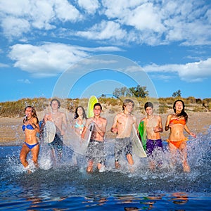 Teenager surfers group running beach splashing