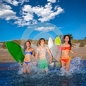 Teenager surfers group running beach splashing