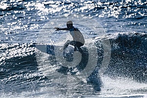 Teenager surfing at the wave in tenerife playa de las americas - white and black wetsuits and beautiful and small wave