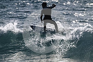 Teenager surfing at the wave in tenerife playa de las americas - white and black wetsuits and beautiful and small wave