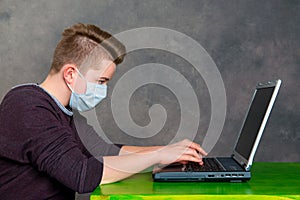 Teenager with surgical mask protect computer from virus