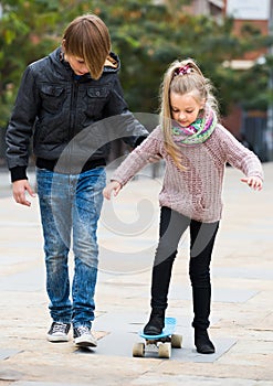 Teenager teaching sister skateboarding