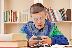 Teenager texting with smartphone while studying