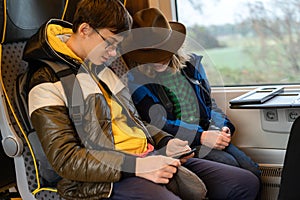 Teenager two boy with phones in hand sitting in a suburban train