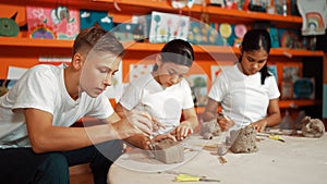 Teenager using carving tool working at clay at pottery workshop. Edification.