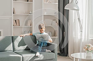 Teenager using laptop on floor near sofa in room, Boy using laptop