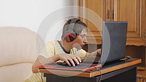 Teenager using laptop. Teen boy with headphones glued to the notebook screen using computer gaming mouse.