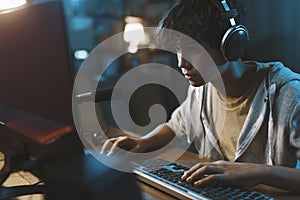 Teenager wearing headphones and playing online video games